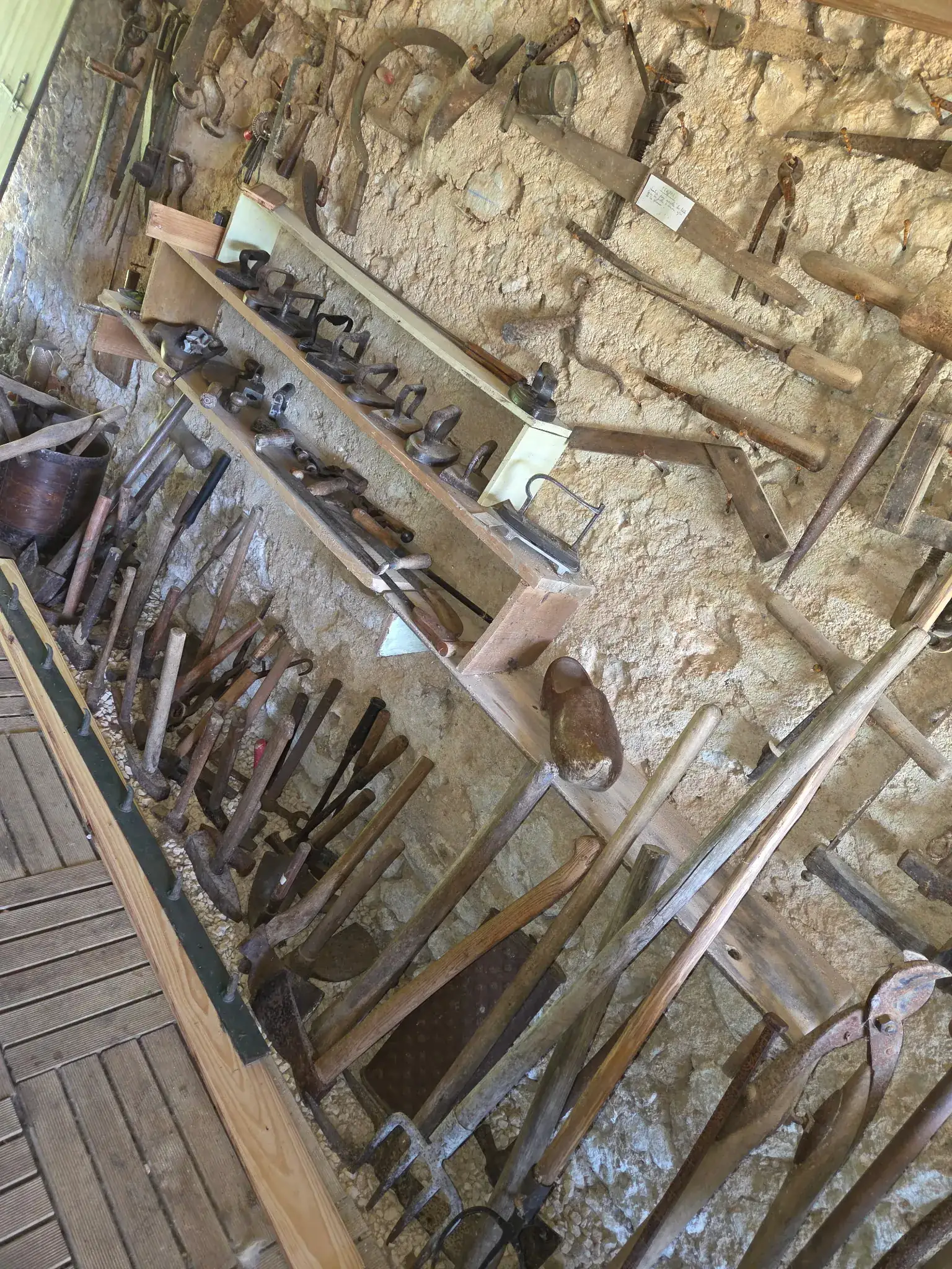 Mur d'outils anciens dans un atelier en pierre