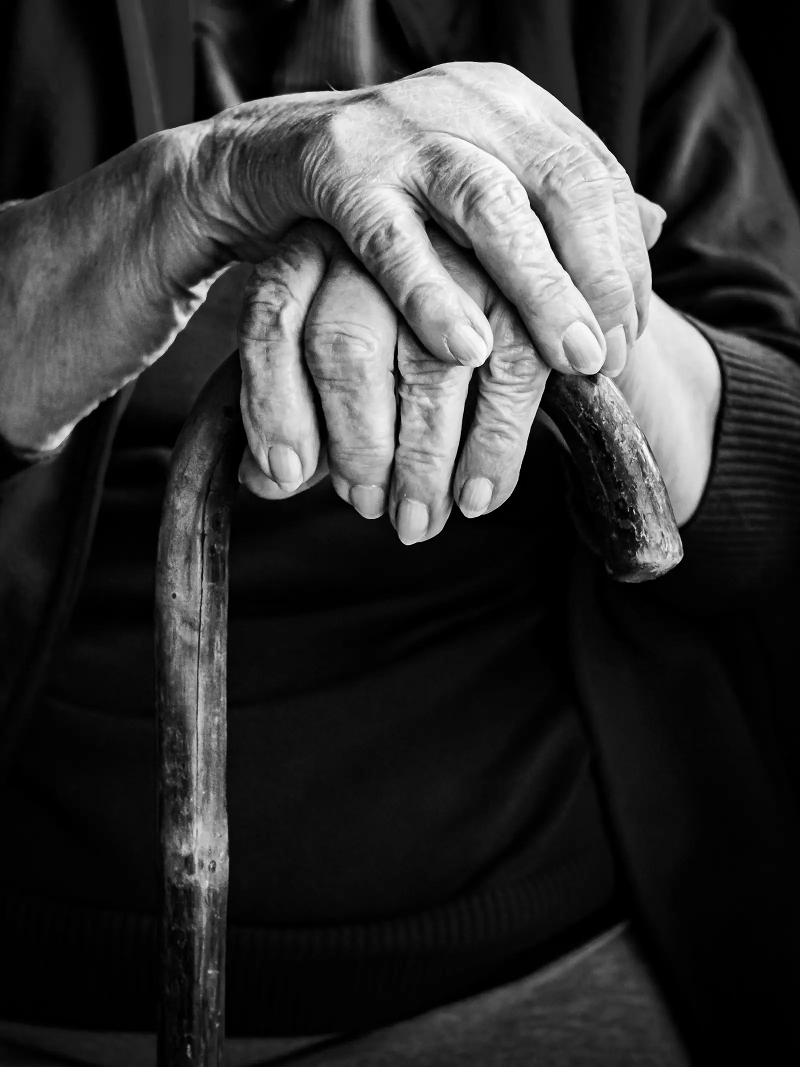 Mains d'une personne âgée posées sur une canne